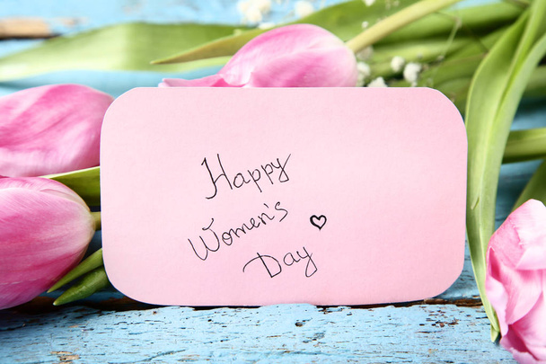 Text Happy Women's Day with pink tulip flowers on blue wooden table - Foto, Imagem