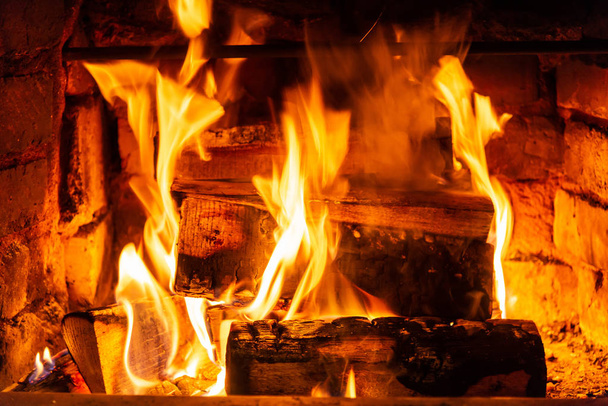 Ohnivé dřevo hoří v krbu. Cihlová trouba poskytuje teplo a teplo z vypálených polen. Hořící uhlíky a plameny zahřívat budovu bytu - Fotografie, Obrázek