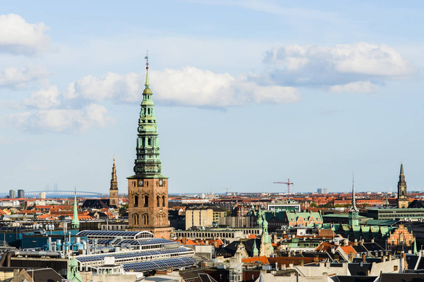 Aerial cityscape shot of old roofs, Nikolaj Kunsthal and Church of Our Saviour from the top of Rundetaarn Round Tower, famous Oresund Bridge between Sweden and Denmark on horizon, Copenhagen - Foto, Imagem