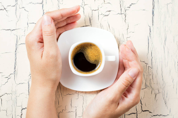 Кавова чашка еспресо на сніданок. Жіночі руки і чашка кави на білому кухонному столі. Вид зверху, простір для копіювання
 - Фото, зображення