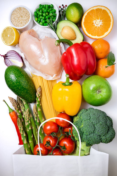 健康食品の背景。紙バッグ肉、果物、野菜、白い背景の上のパスタの健康食品。ショッピングの食品スーパー マーケットの概念です。トップ ビュー - 写真・画像
