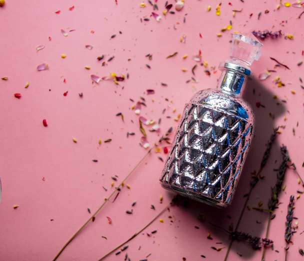 frasco con perfume y pétalos de flores de lavanda sobre fondo rosa
 - Foto, imagen