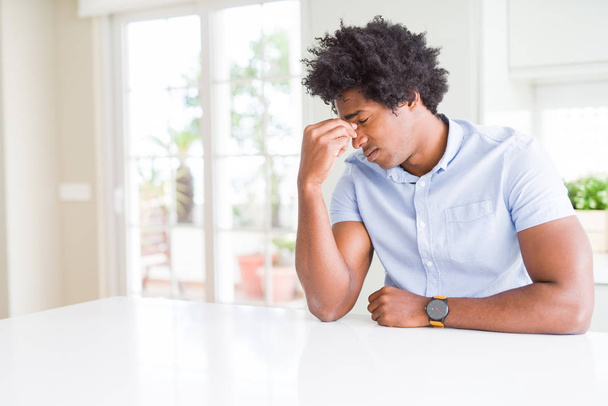 Afro-Amerikaanse zakenman moe wrijven neus en ogen, vermoeidheid en hoofdpijn gevoel. Stress en frustratie concept. - Foto, afbeelding