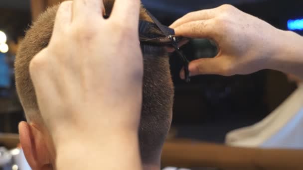 Arms of barber trimming hair of client in barbershop. Male hands of hairdresser combing and cutting hair of customer with hairbrush and scissors in salon. Hairstyling process. Rear view Slow motion - Footage, Video