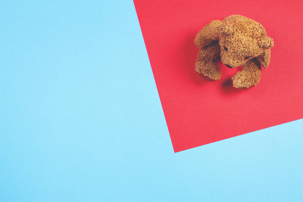 Іграшка з плюшевого ведмедя на червоно-синьому тлі. Вид зверху
 - Фото, зображення