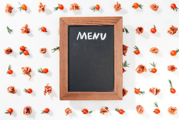chalk board with menu lettering among cherry tomatoes, prosciutto and leaves - Photo, Image