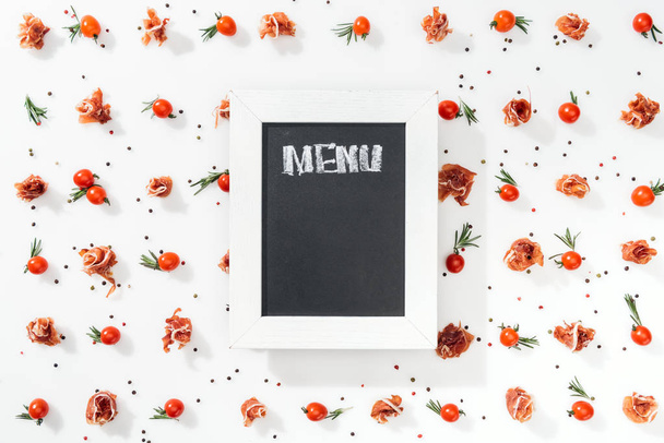 vista superior de pizarra con letras de menú entre tomates, prosciutto, especias y hojas
  - Foto, Imagen