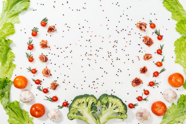 top view of tomatoes, lettuce leaves, prosciutto, broccoli, spices and garlic  - Foto, Bild