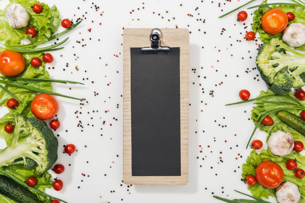 top view of empty clipboard with tomatoes, lettuce leaves, cucumbers, onion, spices and garlic - Fotoğraf, Görsel