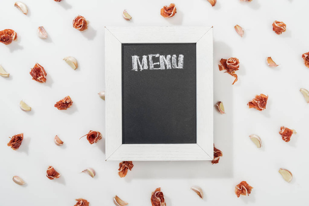 top view of chalk board with menu lettering among prosciutto and garlic cloves - Fotó, kép