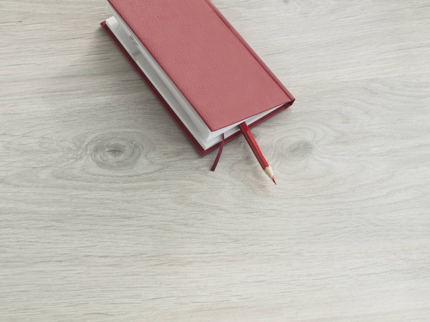 Accesorios de oficina: un bloc de notas rojo y lápices rojos sobre un escritorio gris de madera. Vista superior, Copiar espacio
. - Foto, Imagen