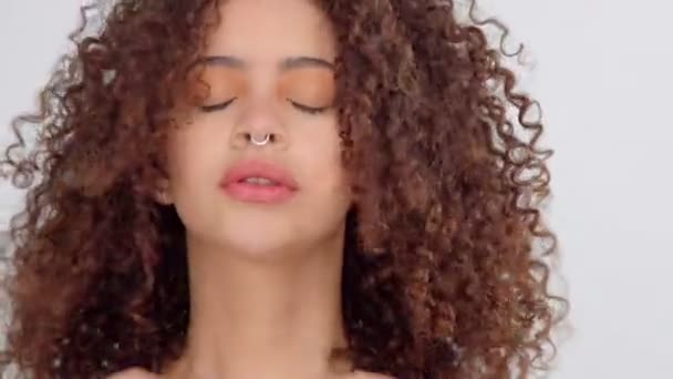 gemengd ras zwarte vrouw met sproeten en krullend haar in studio op witte poses aan een camera - Video