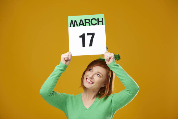 Женщина показывает календарь с датой Дня Святого Патрика
 - Фото, изображение