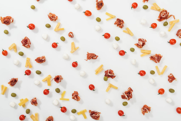 top view of olives, prosciutto, mozzarella, cut cheese and cherry tomatoes - 写真・画像