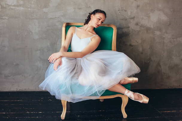 Balletttänzerin Ballerina in schönem hellblauen Kleid Tutu-Rock posiert sitzend auf Vinage Stuhl im Loft-Studio - Foto, Bild