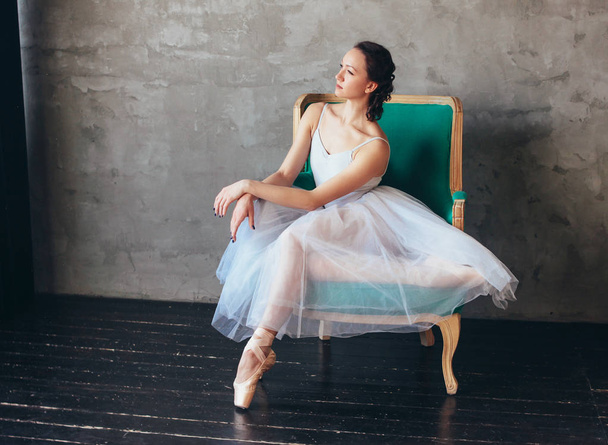 Ballet bailarina bailarina em bela luz azul vestido saia tutu posando sentado na cadeira vinagre no estúdio loft
 - Foto, Imagem