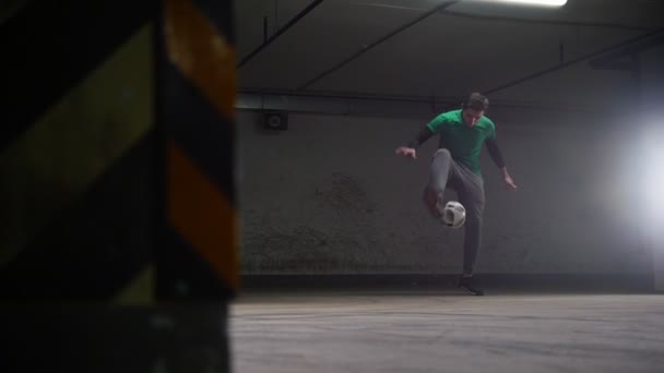 Underground parking. Athletic soccer man training his football skills - Кадры, видео