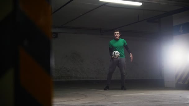 地下駐車場。スポーツ サッカー男は彼のサッカーのスキルをトレーニングします。ボールを蹴る、空気のそれを投げ、首にボールをキャッチ - 映像、動画
