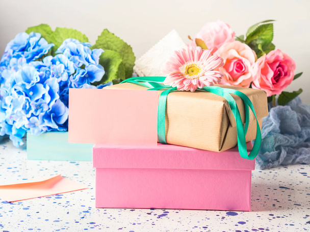 Carta rosa vuota e scatole regalo impilate. Fiori
 - Foto, immagini