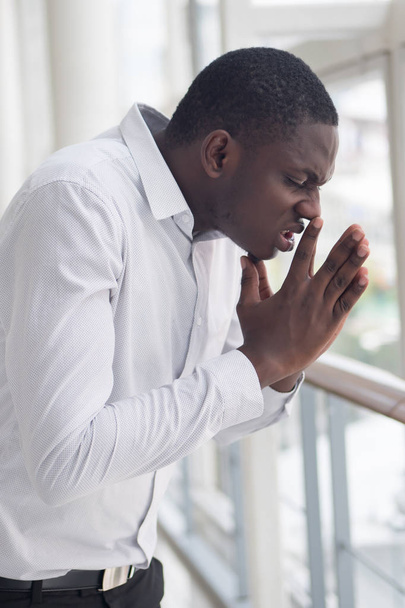 Hombre africano enfermo estornudando debido a la alergia; Retrato de hombre africano alérgico estornuda debido al frío, gripe, alergia, aire contaminado, polvo fino; contaminación del aire, concepto de enfermedad pulmonar; Modelo de hombre africano
 - Foto, imagen
