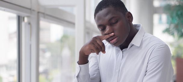 Sick African man with runny nose; Portrait of ill black man suffering from runny nose due to cold; flu; allergy; polluted air; dust; smog; air pollution sickness concept; African young adult man model - Photo, Image