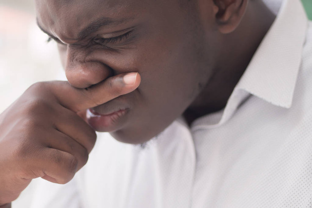Больной африканский мужчина с насморком; портрет больного черного мужчины, страдающего от насморка из-за холода; грипп; аллергия; загрязненный воздух; пыль; смог; концепция загрязнения воздуха; африканская модель молодого мужчины
 - Фото, изображение