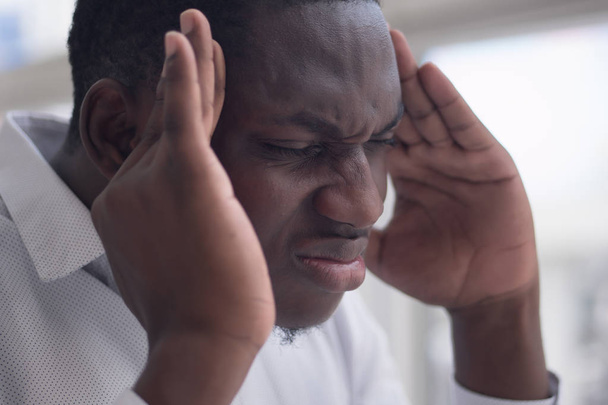 portrait of stressed sick black man with headache; ill african man suffers from headache, vertigo, dizziness, migraine, stress, depression, hangover concept; adult african man model - Фото, зображення
