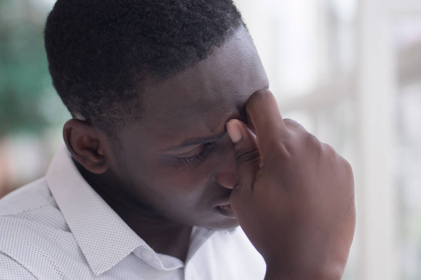 Portrait eines gestressten schwarzen Mannes mit Kopfschmerzen; kranker afrikanischer Mann leidet unter Kopfschmerzen, Schwindel, Schwindel, Migräne, Stress, Depressionen, Katerstimmung; erwachsenes afrikanisches Männermodell - Foto, Bild