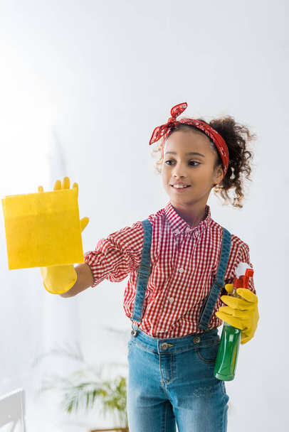 cute african american child with yellow rag and green spray bottle - Foto, Imagem