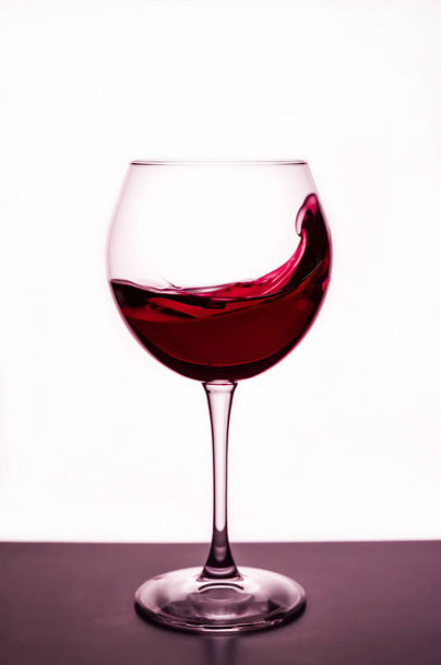 splashes of red wine in a wineglass - still life on the theme of drink - Фото, изображение