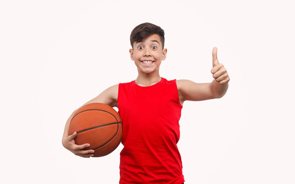 Cheerful boy with ball gesturing thumb up - Zdjęcie, obraz