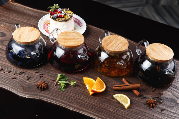 diverse soorten thee in theepotten op een houten tafel. selectieve aandacht - Foto, afbeelding