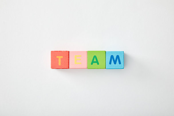 top view of team lettering made of multicolored cubes on grey background - Foto, imagen