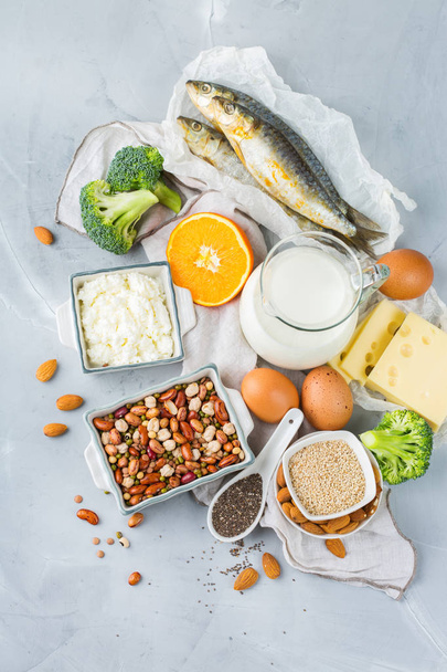 Alimentación equilibrada, concepto de alimentación saludable. Surtido de fuentes de alimentos ricos en calcio, frijoles, productos lácteos, sardinas, brócoli, semillas de chía, almendras en una mesa de cocina
 - Foto, imagen