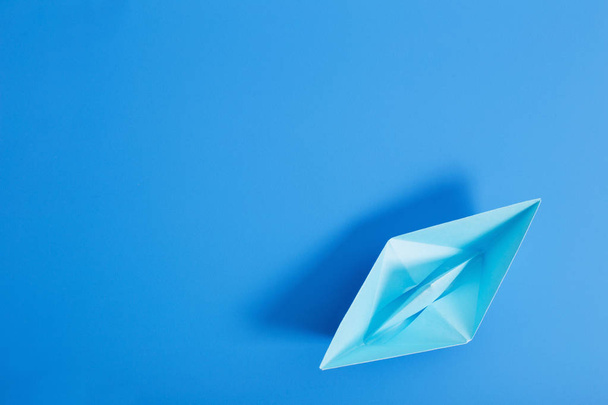 paper boat on blue paper background - Фото, изображение