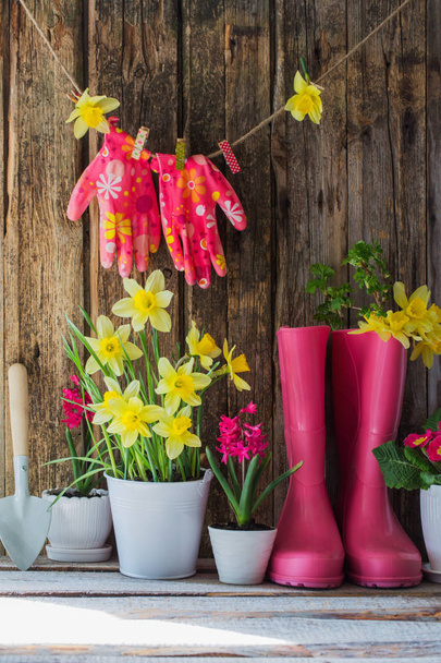 rubber boots and spring flowers on wooden background - Foto, afbeelding