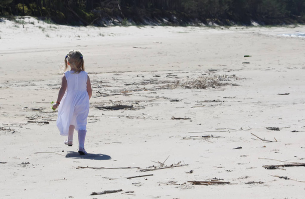 niña jugando en un vestido blanco en la playa - Foto, Imagen