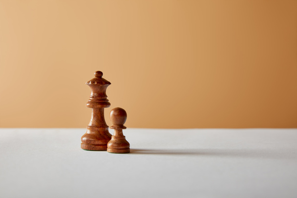 wooden queen and pawn pieces on white table and beige background - Photo, Image