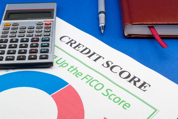 Credit score report with calculator on a blue table. - Photo, Image