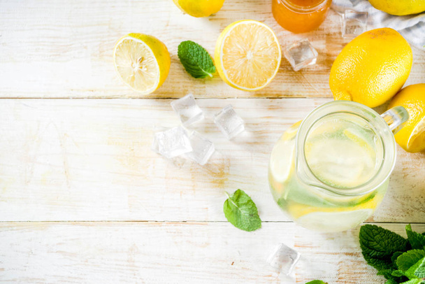 Zelfgemaakte zure cocktail limonade, met verse citroenen, munt en honing, witte houten achtergrond kopie ruimte - Foto, afbeelding