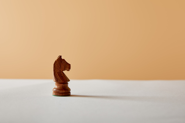 wooden knight piece on white table and beige background - Φωτογραφία, εικόνα