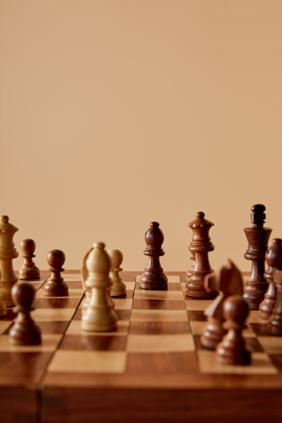 selective focus of chess on wooden chess board and beige background - Foto, Imagem
