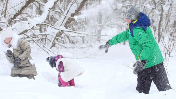 Due bambine che giocano con il loro amico nella neve nella foresta invernale. Lancio di palle di neve
 - Foto, immagini