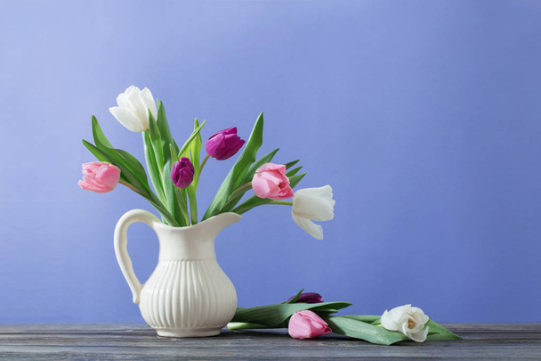 tulips in jug on violet background - Photo, Image