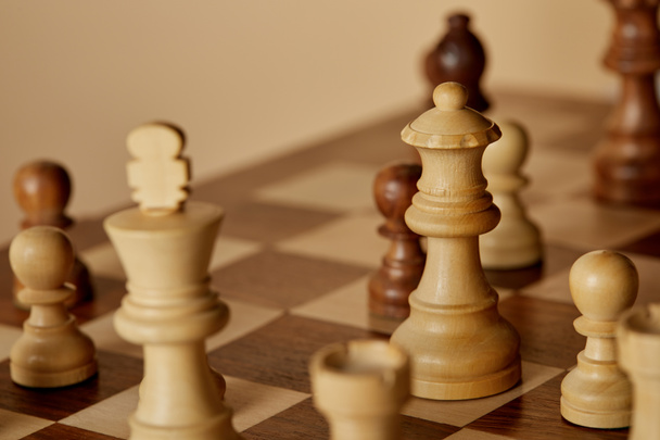 selective focus of wooden chess pieces on chess board and beige background - Photo, Image
