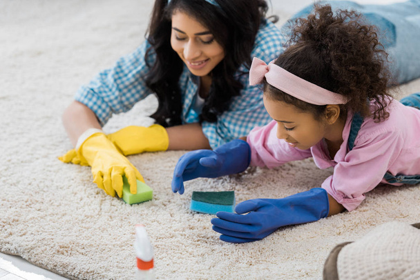 pretty african american woman with adorable daughter cleaning carpet with sponges - Photo, Image