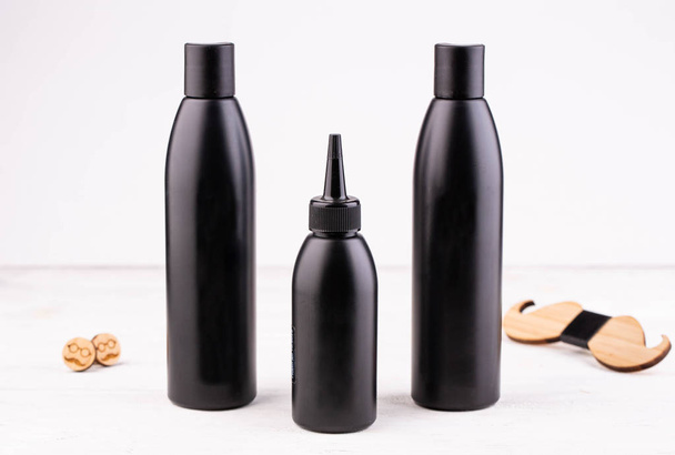 Black bottles from under shampoo, oil and the conditioner with the men accessories - Фото, изображение