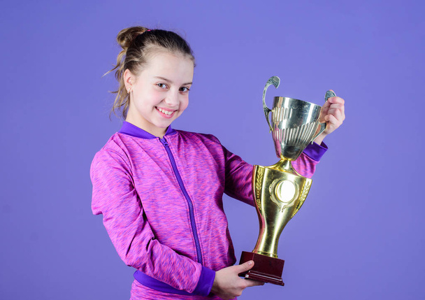 Sport achievement. Celebrate victory. Girl hold golden goblet. Importance of capturing evidence of kids progress. Proud of her achievement. Celebrating childrens achievements great and small - Foto, immagini