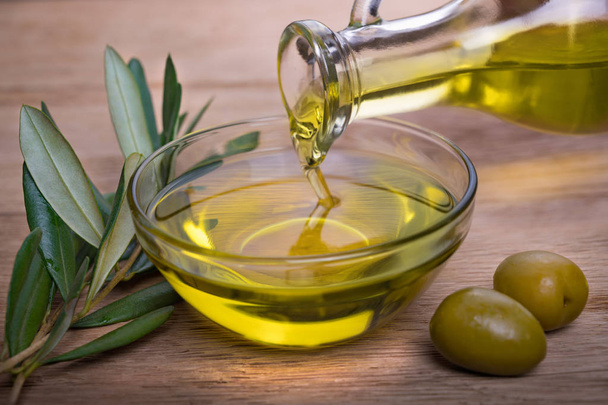 Bowl with olive oil on wooden table - Foto, Imagen