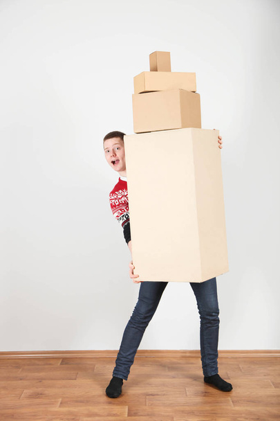 Young smiling guy with bunch of boxes on neutral background. Concept delivery, courier, moving. - Photo, Image